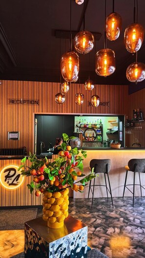 A reception area with a wooden wall, a reception desk, a bar area, and a plant centerpiece. - Hotel Parc & Lac (Montreux)