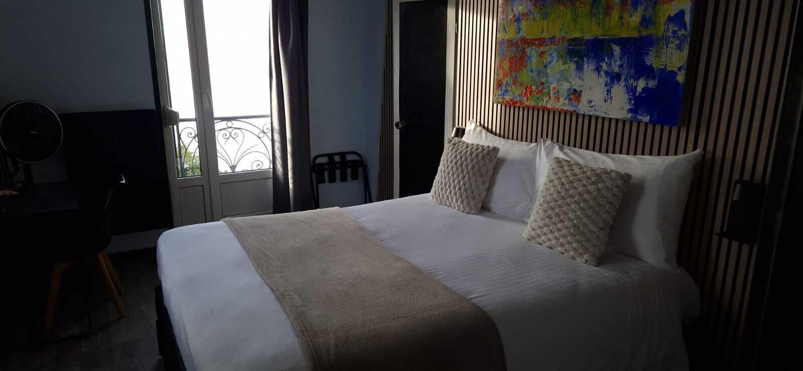 A hotel room with a large bed, a desk, a chair, and a window with a view of the outside.