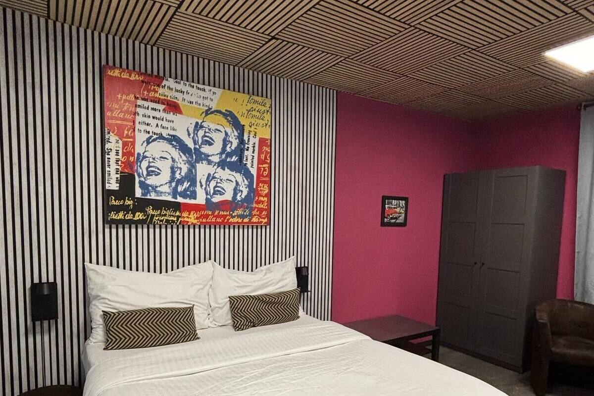 A bedroom with a bed, a wall-mounted artwork, a wardrobe, and a chair.