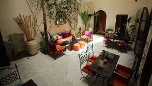 Un patio amplio con zona de comedor, mobiliario para sentarse y una planta grande en maceta.