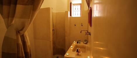 A bathroom with a shower, a sink with candles, and a window.