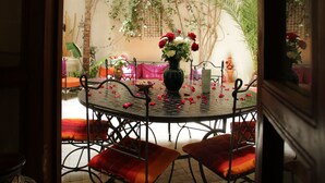 Un comedor con una mesa redonda, sillas y un florero con flores.