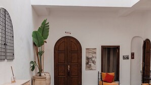 Zona de piscina con una puerta de madera, una silla con cojín y una planta en maceta.
