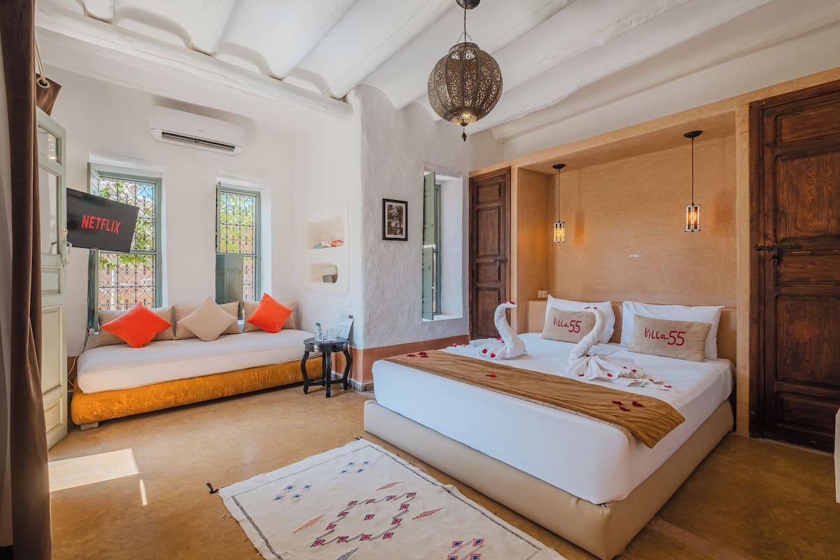 Una habitación de hotel con una cama grande, un sofá cama, un televisor y una puerta de madera.