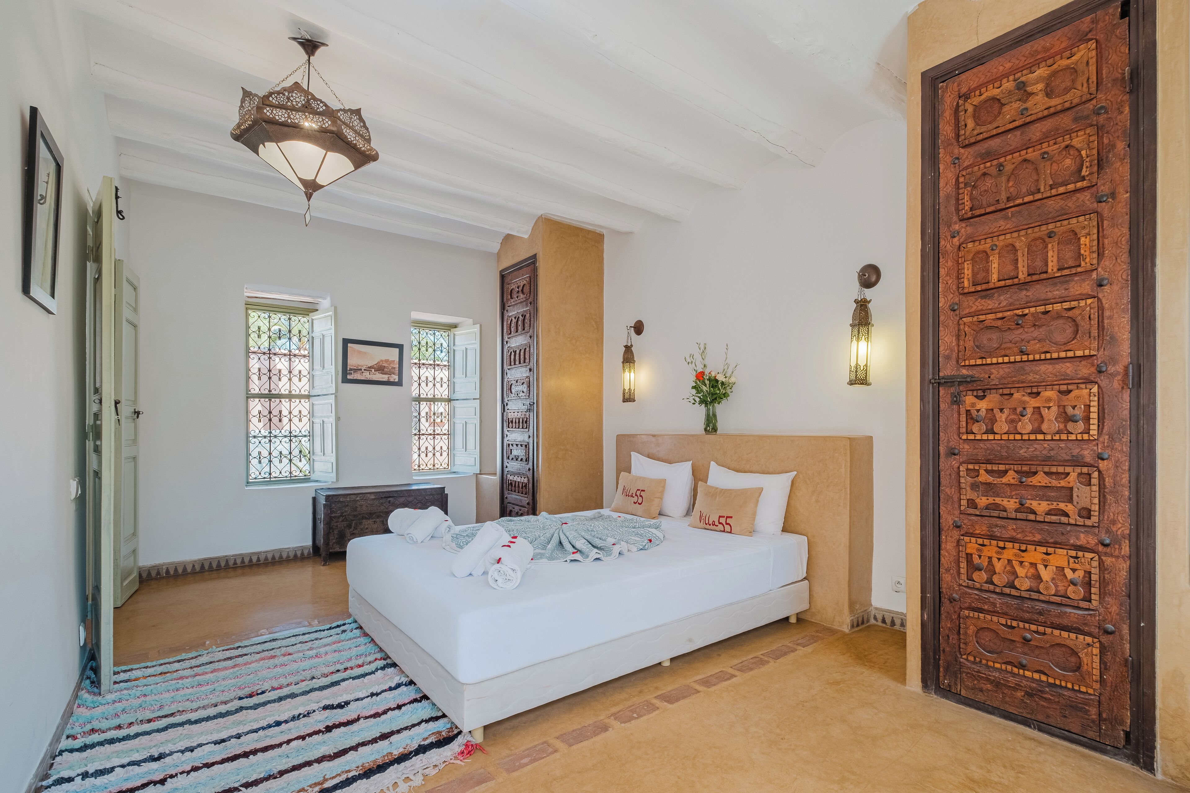 A spacious bedroom with a large bed, a wooden door, and a decorative ceiling light.