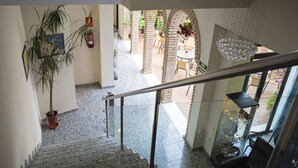 Eine Treppe führt zu einer Außenpatio-Terrasse mit Blumentöpfen und einem Glasgeländer.