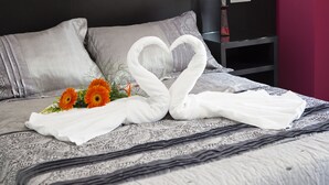 Ein ordentlich bezogenes Bett mit einer herzförmigen Handtuchgestaltung und orangefarbenen Blumen.