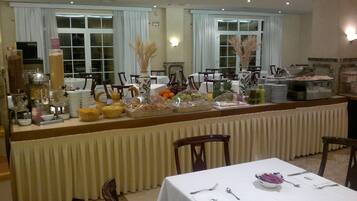 Disposição de buffet com diversos alimentos e uma mesa posta para refeição.
