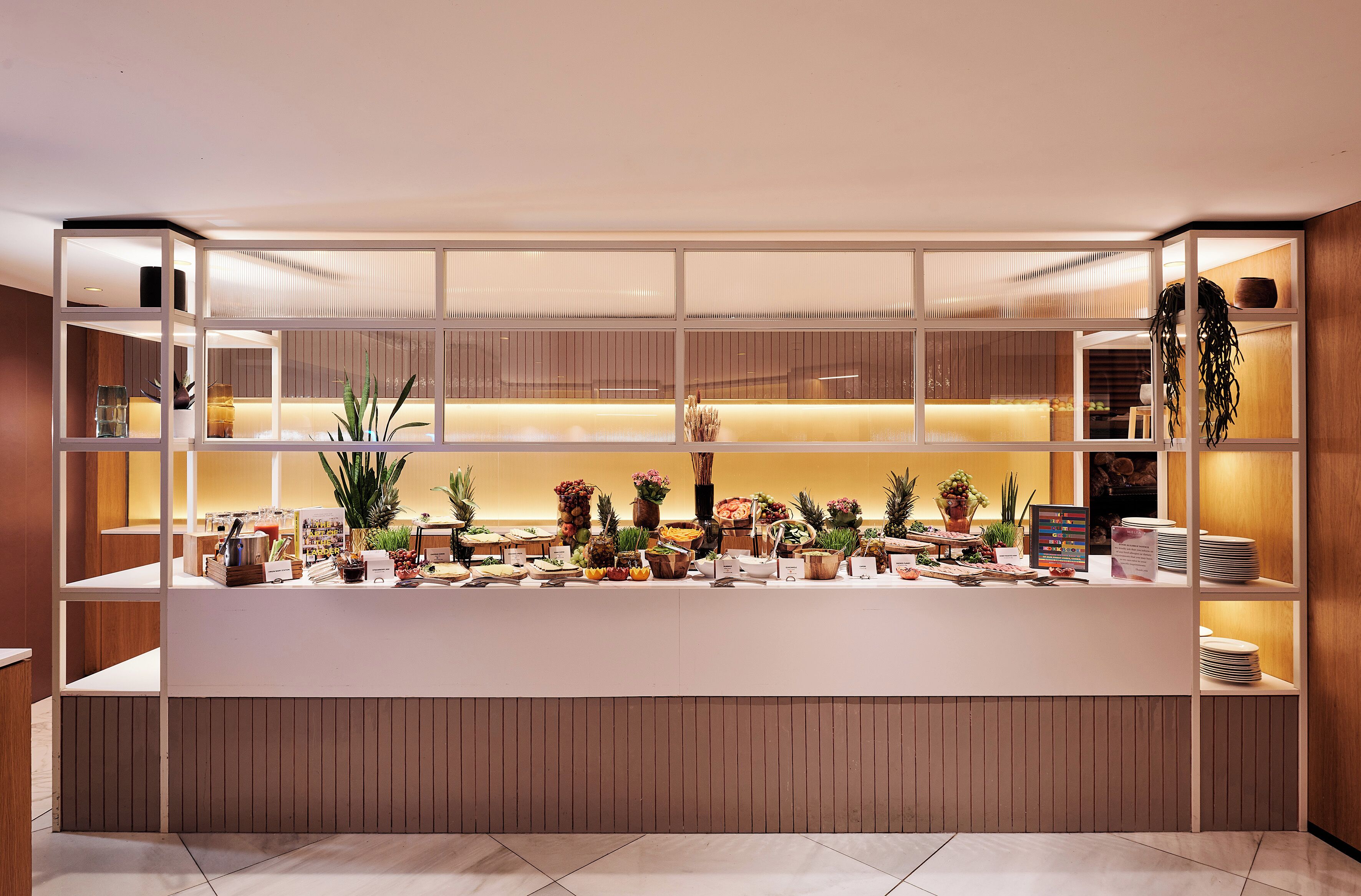 A reception area with a counter, shelves with plants, and a sign.