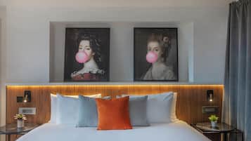 Una habitación de hotel moderna con una cama grande, dos mesitas de noche, un cabecero de madera y dos obras de arte enmarcadas en la pared.