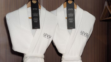 Two white robes hanging on wooden hangers with tags labeled "LEVEL".