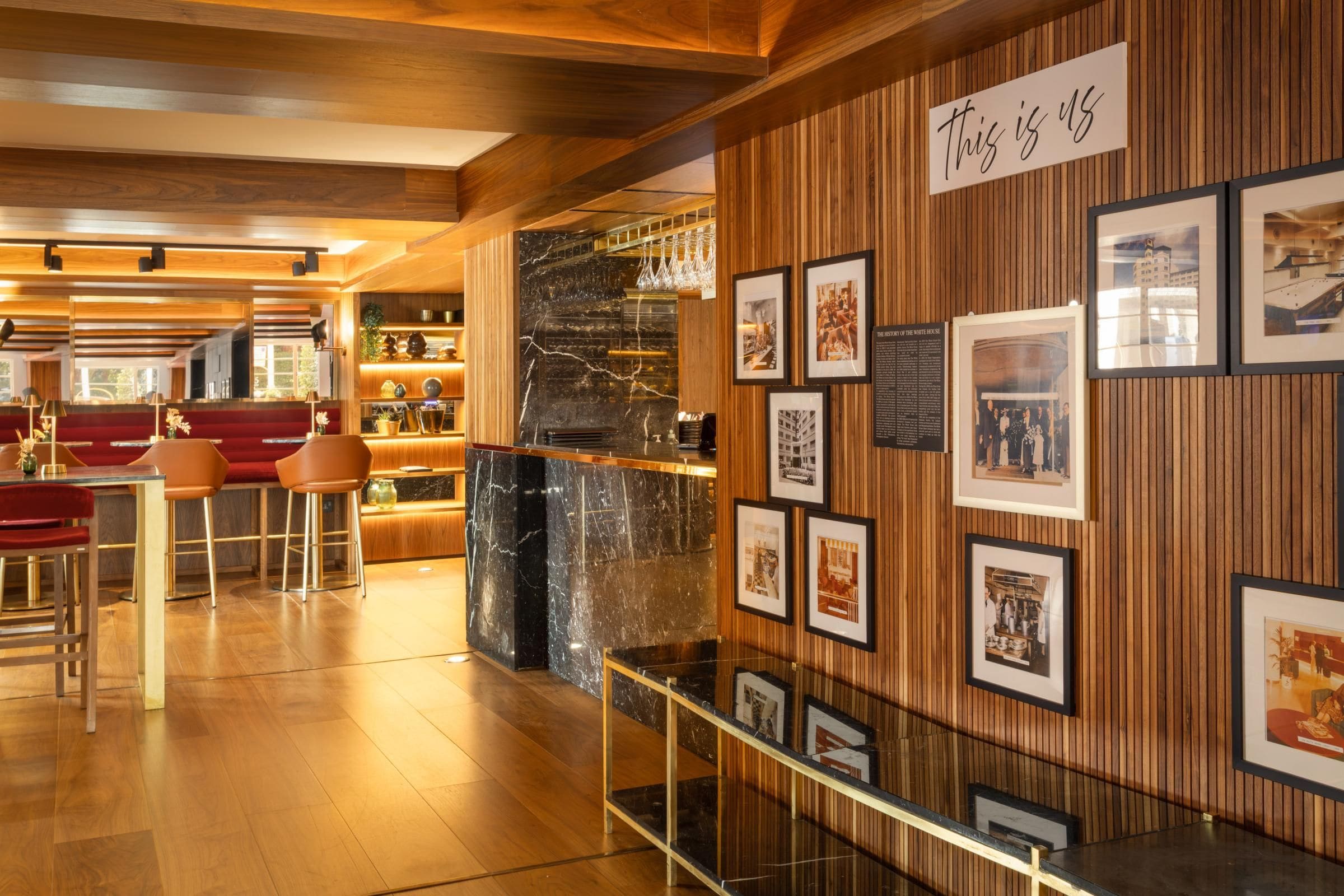 Interior de restaurante con paneles de madera, una barra de mármol y fotografías enmarcadas en la pared.