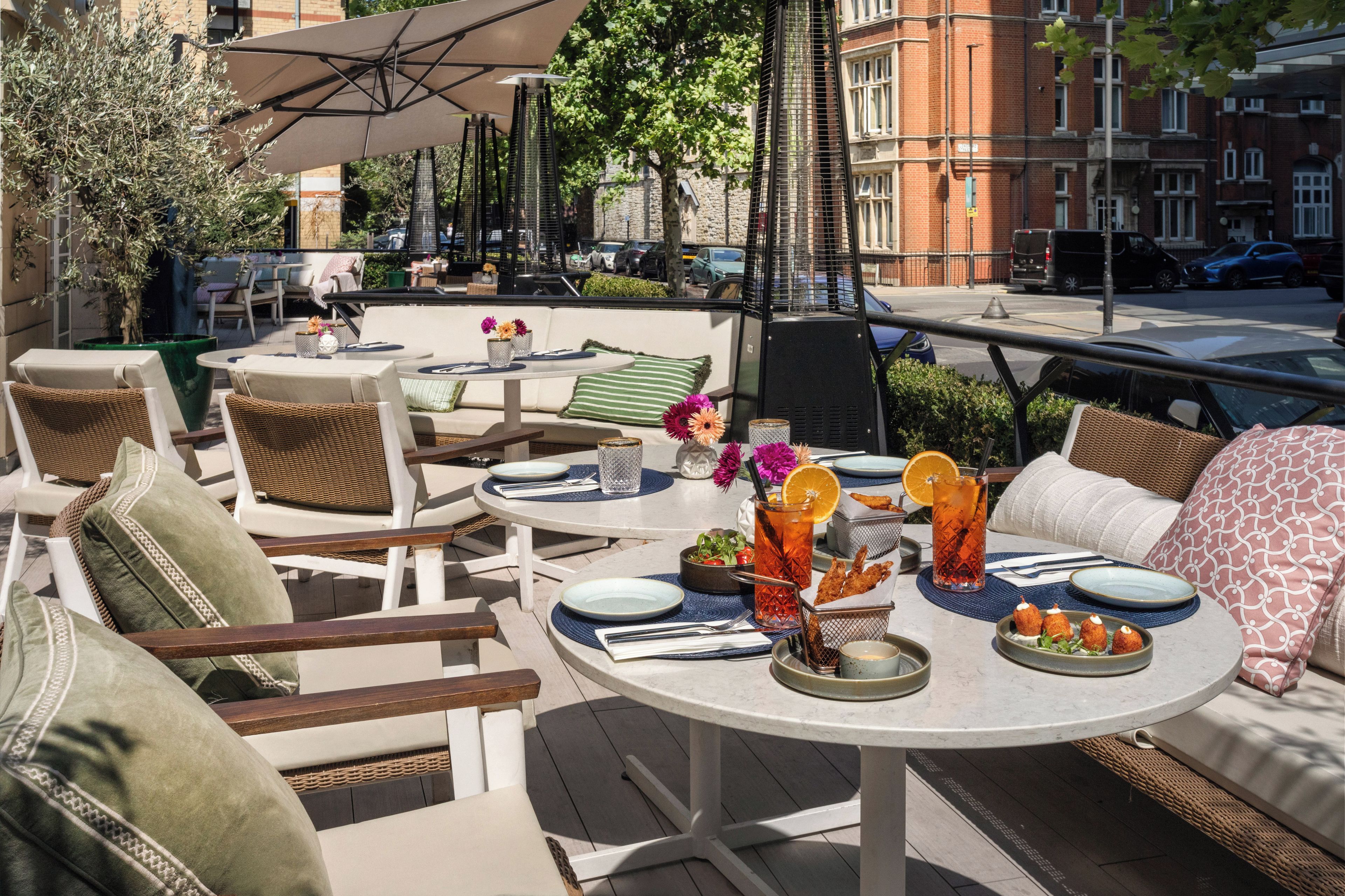 An outdoor seating area with round tables, chairs, and umbrellas.