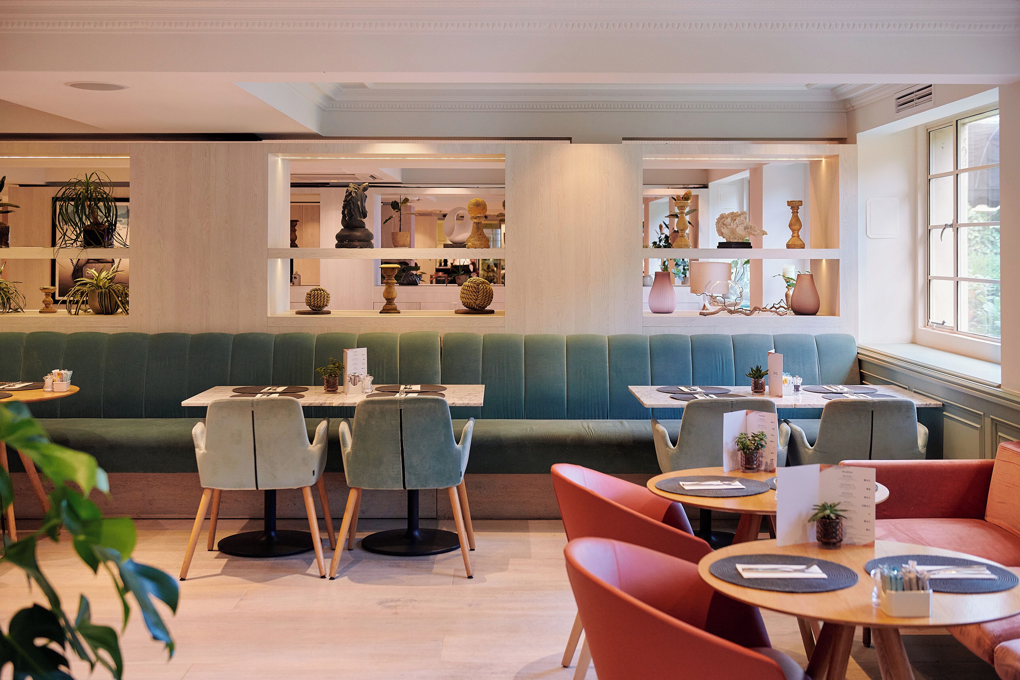 A restaurant with booths and tables, some with plants on the tables.