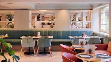 A restaurant with booths and tables, some with plants on the tables.