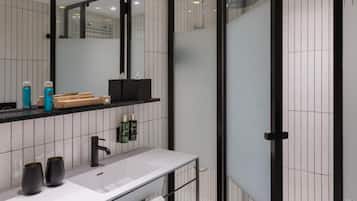 A modern bathroom with a large mirror, a white sink, and a glass shower enclosure.