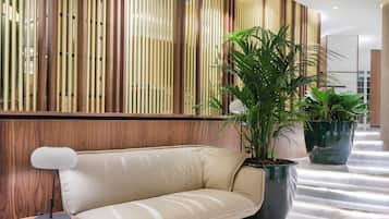 A modern interior with a sofa, a lamp, and potted plants.