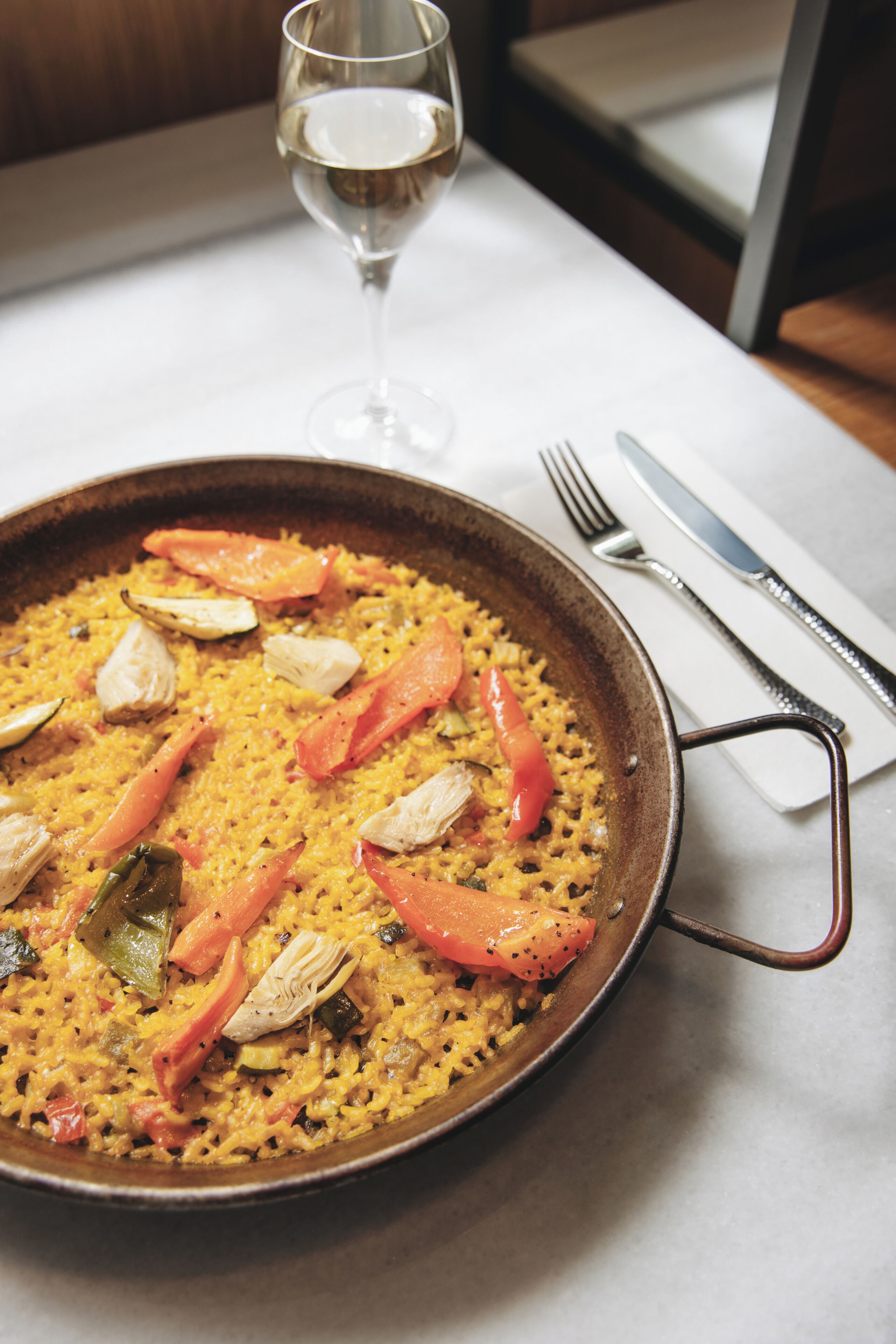 Una paellera grande de paella con verduras y pollo sobre una mesa.