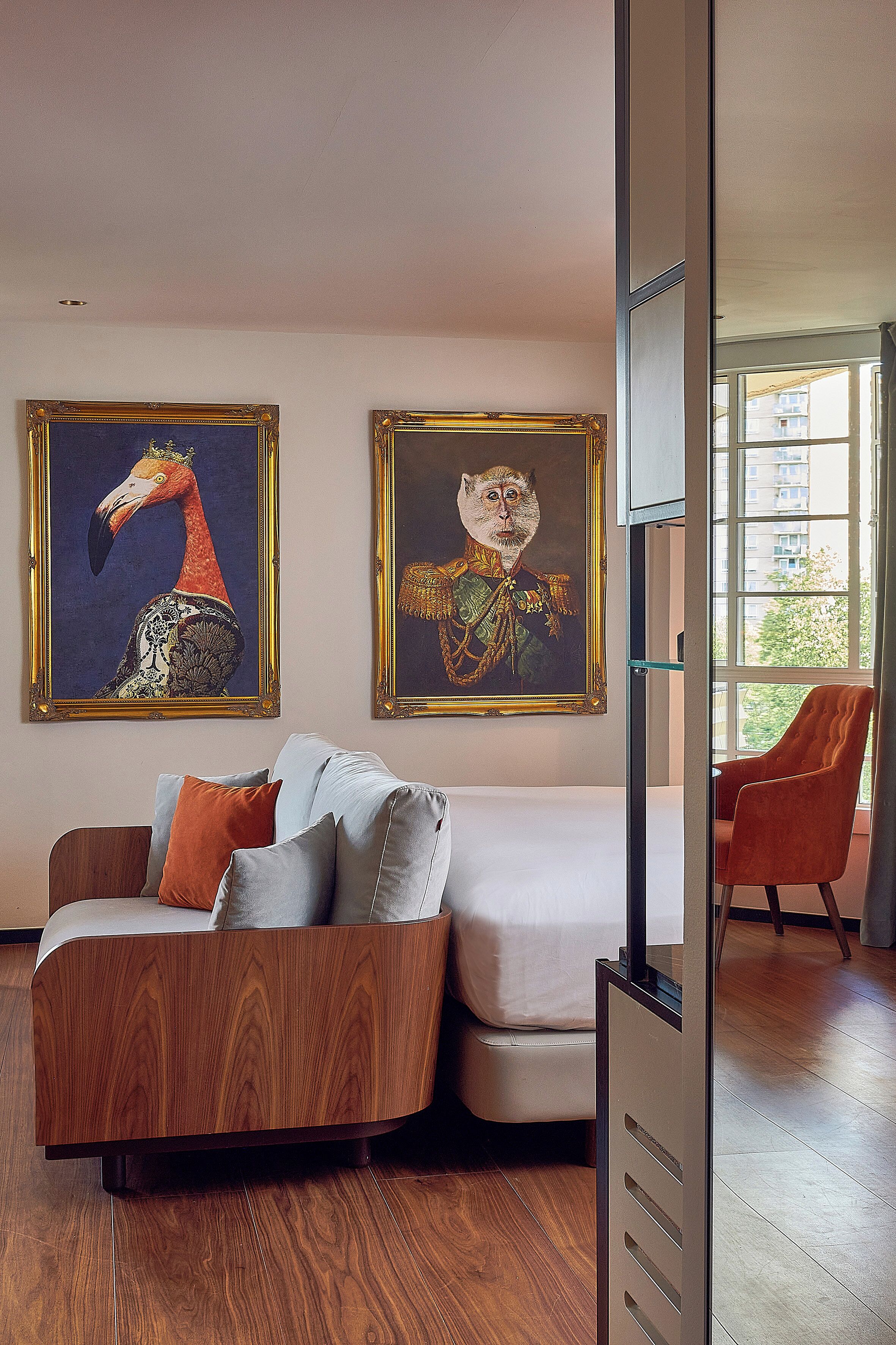 Una sala de estar moderna con un sofá de madera, una cama y dos cuadros enmarcados en la pared.