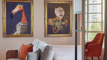 Una sala de estar moderna con un sofá de madera, una cama y dos cuadros enmarcados en la pared.