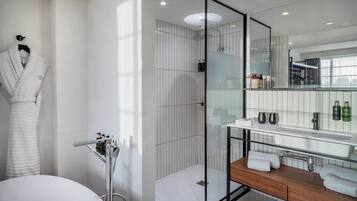 Un baño moderno con cabina de ducha de vidrio, tocador de madera y un espejo grande.