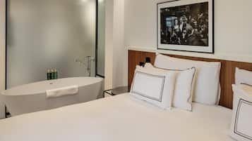 A modern hotel room with a large bed, a wooden headboard, and a framed photograph on the wall.