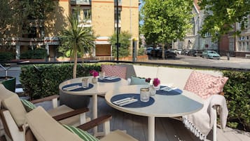 An outdoor seating area with round tables, chairs, and cushions.