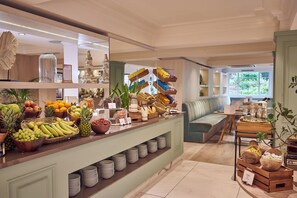 A buffet area with various fruits, bowls, and a seating area with a bench and table. - The Level at the Melia White House (London)