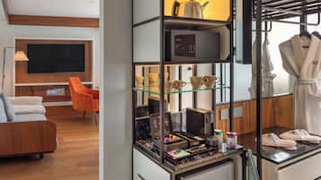 Habitación de hotel con zona de estar, kitchenette y perchero para bata y zapatillas.