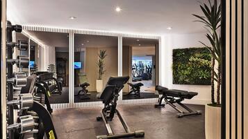 A gym with exercise equipment, a mirrored wall, and a green wall with plants.