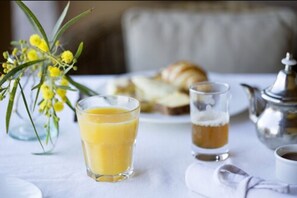 A breakfast setting with a glass of orange juice, a glass of coffee, a croissant, and a silver teapot on a table. - Le Palais Paysan (Tameslouht)