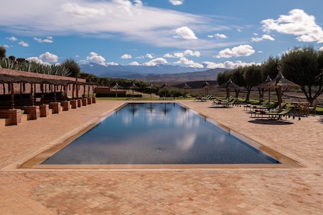 Una piscina al aire libre, sombrillas, sillones reclinables de piscina