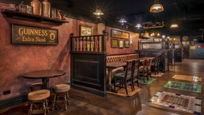 Un área de bar acogedor con taburetes de madera, una barra y un cartel de Guinness Extra Stout.