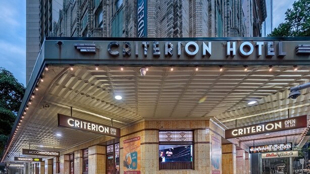 Entrada del Hotel Criterion con un cartel luminoso, acceso cubierto y fachada de azulejos.
