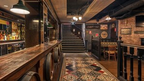 Una zona de bar con mostrador de madera, una escalera y suelo con diseño.