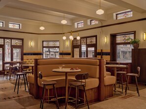 A restaurant interior with a booth seating area, bar stools, and a view through the windows. - Criterion Hotel Sydney (Sydney)