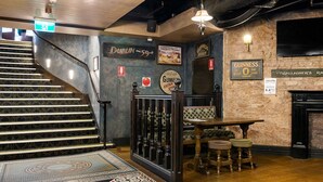 Una escalera con suelo estampado que conduce a un área de bar con taburetes y una mesa.
