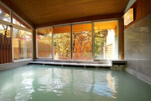 A hot tub area with large windows and a view of autumn trees. - Chuzenji Kanaya Hotel (Nikko)