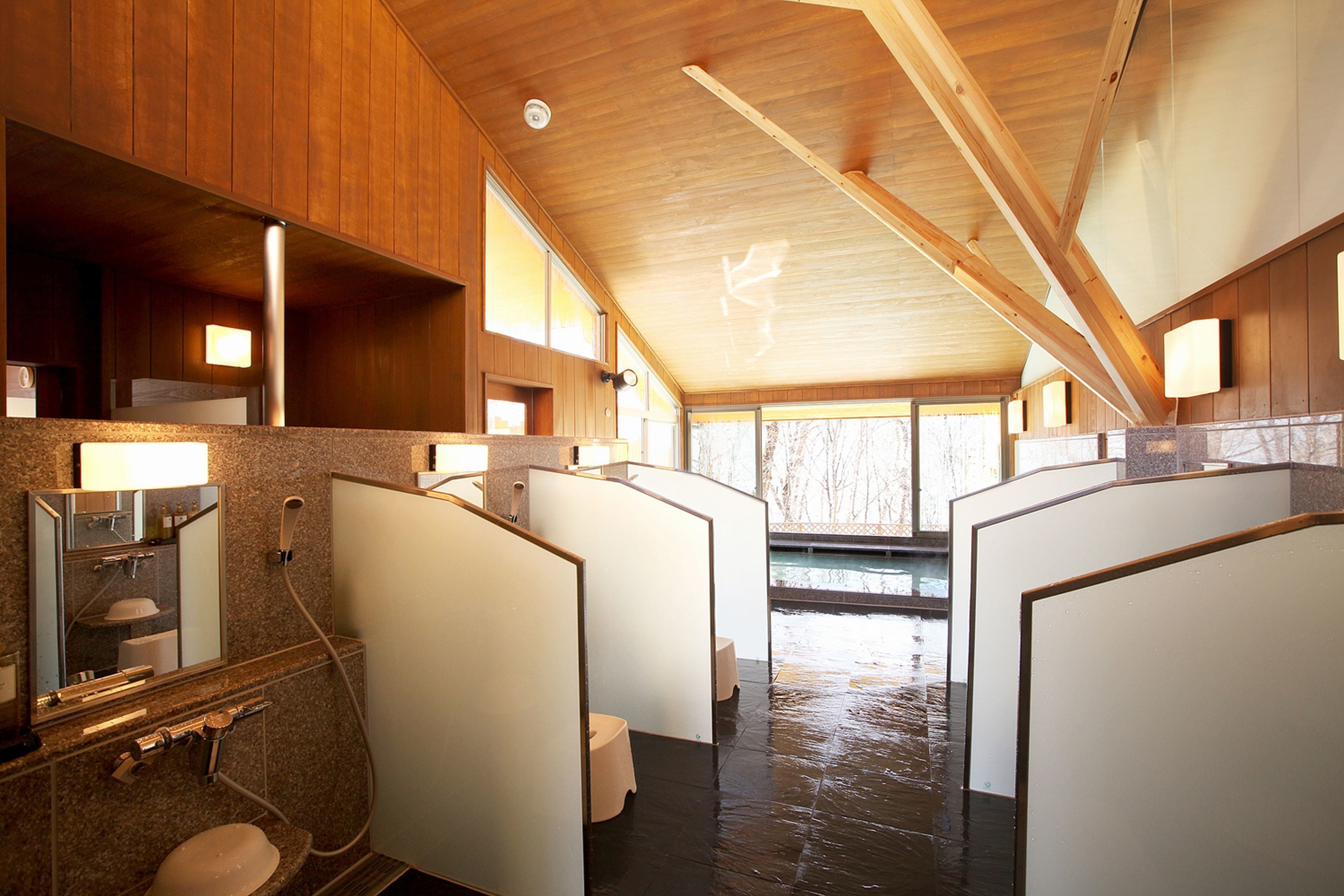 Une salle de bain moderne avec un lambris en bois, des douches individuelles, un lavabo et un miroir.