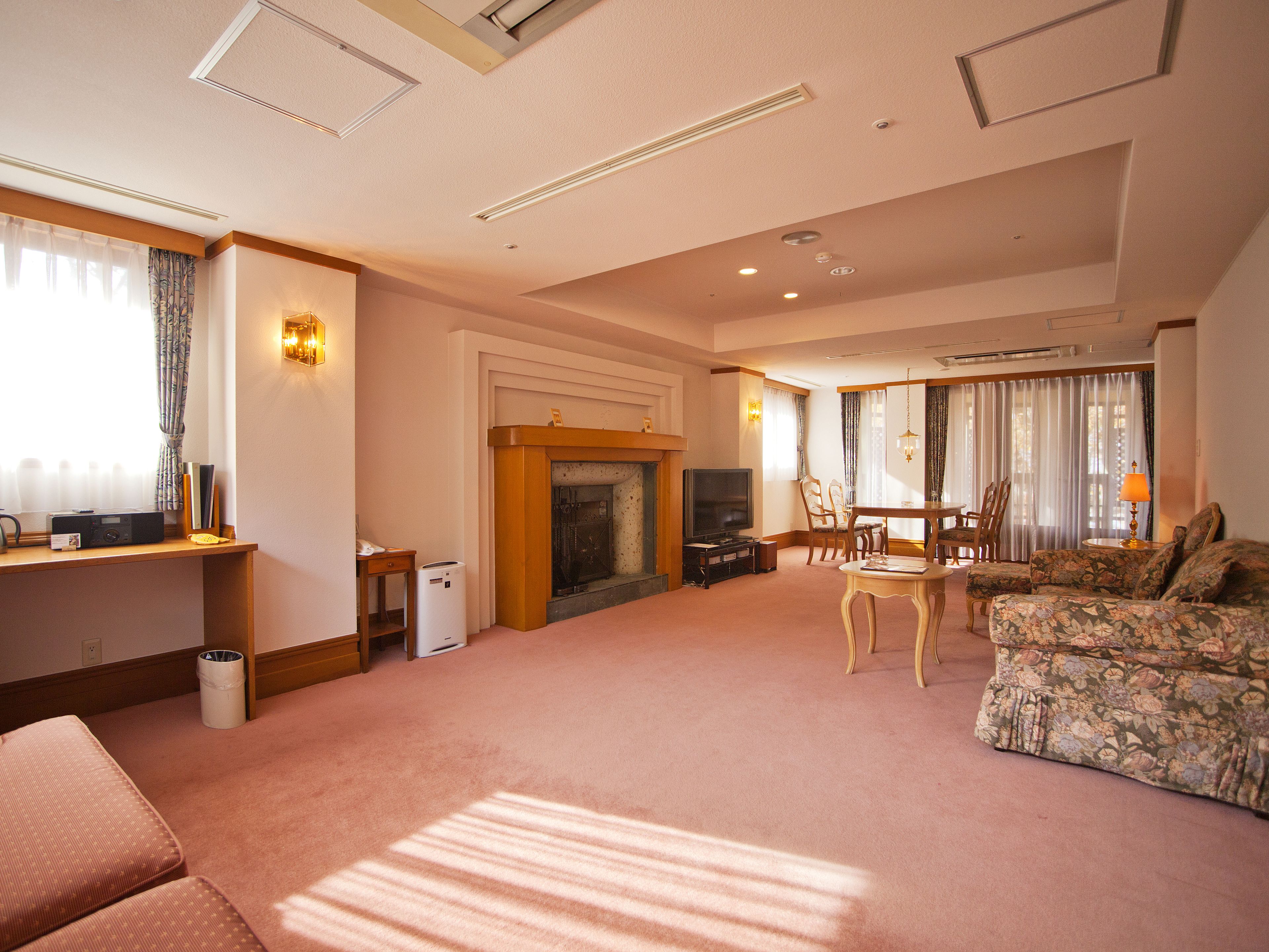 A living room with a fireplace, a television, a dining table with chairs, and a sofa.