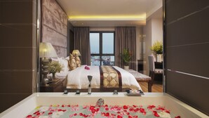 Ein modernes Hotelzimmer mit einem großen Bett, einer mit Rosenblättern gefüllten Badewanne und Blick auf die Stadt durch das Fenster.