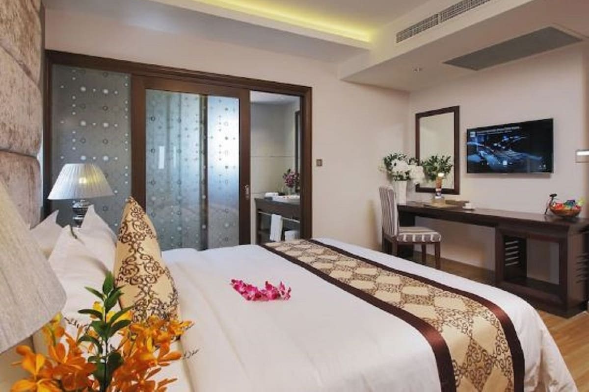 A hotel room with a bed, a desk, a television, and a bathroom with a shower and toilet.