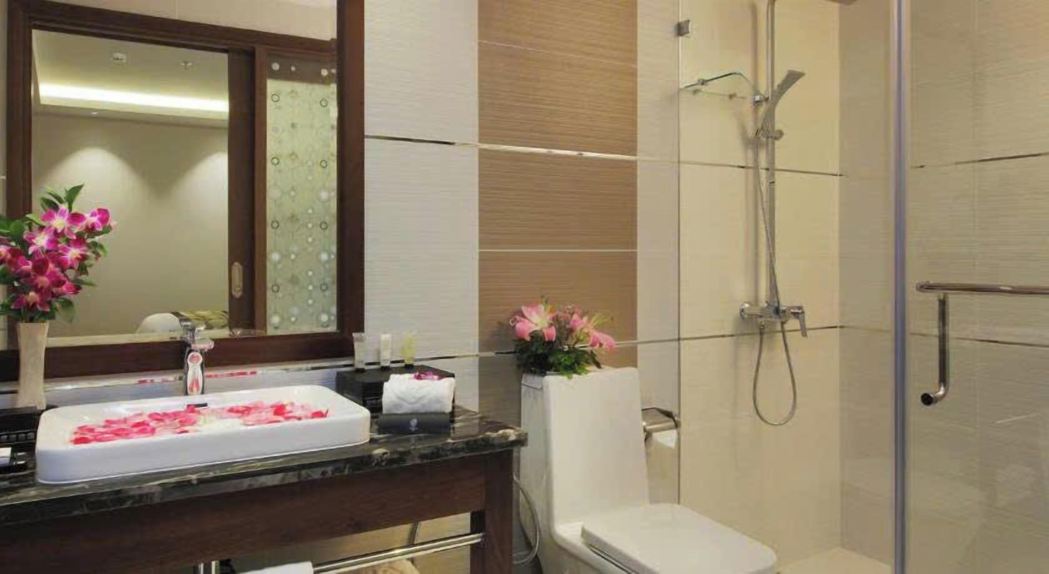 Ein Badezimmer mit Waschbecken, Spiegel, Dusche und Toilette.