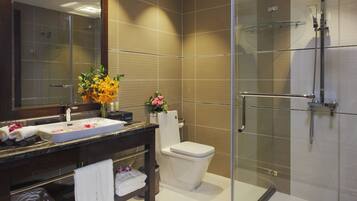 A modern bathroom with a glass-enclosed shower, a large mirror, and a vanity with a sink and towel rack.