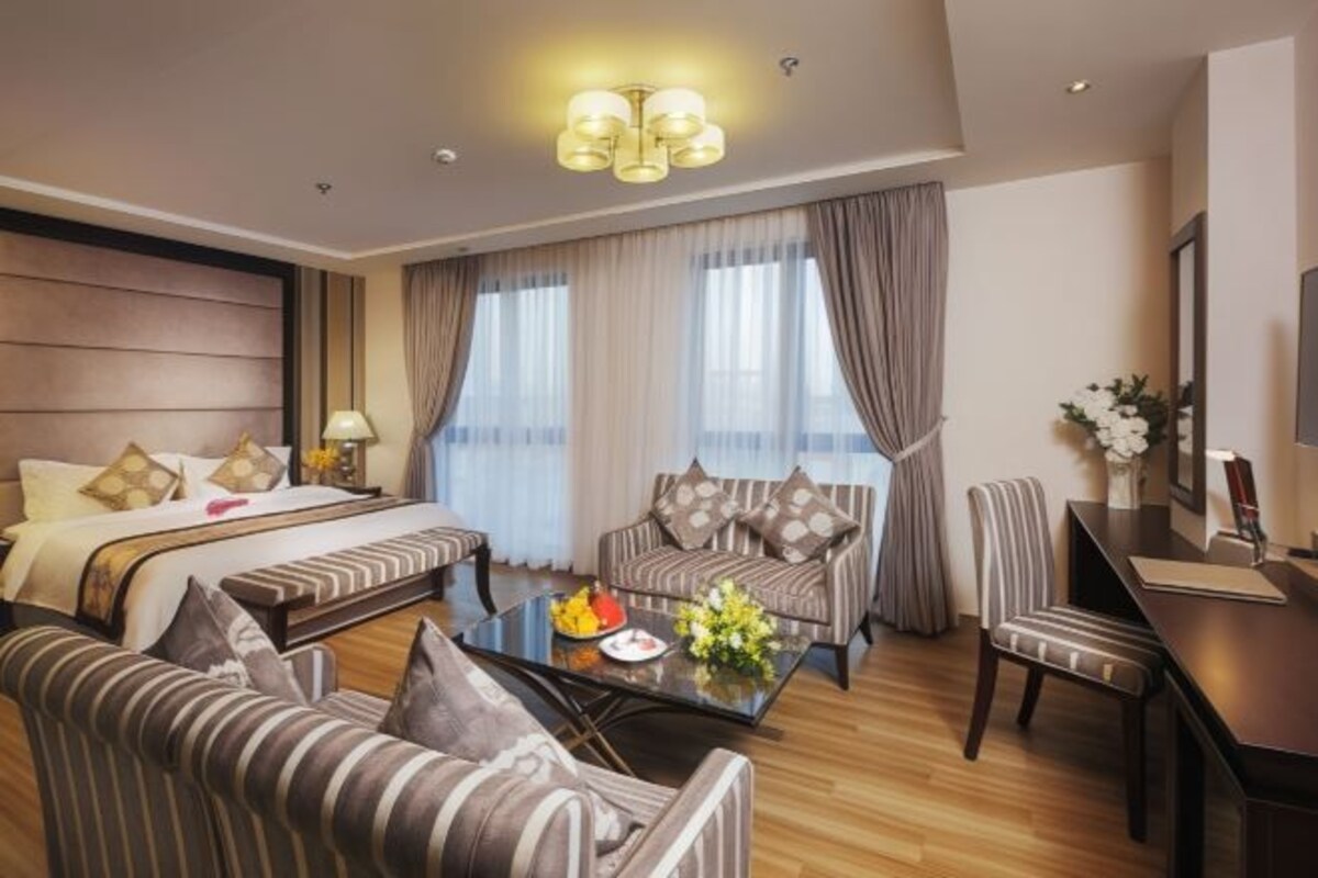A hotel room with a bed, two sofas, a coffee table, a desk, and a TV.