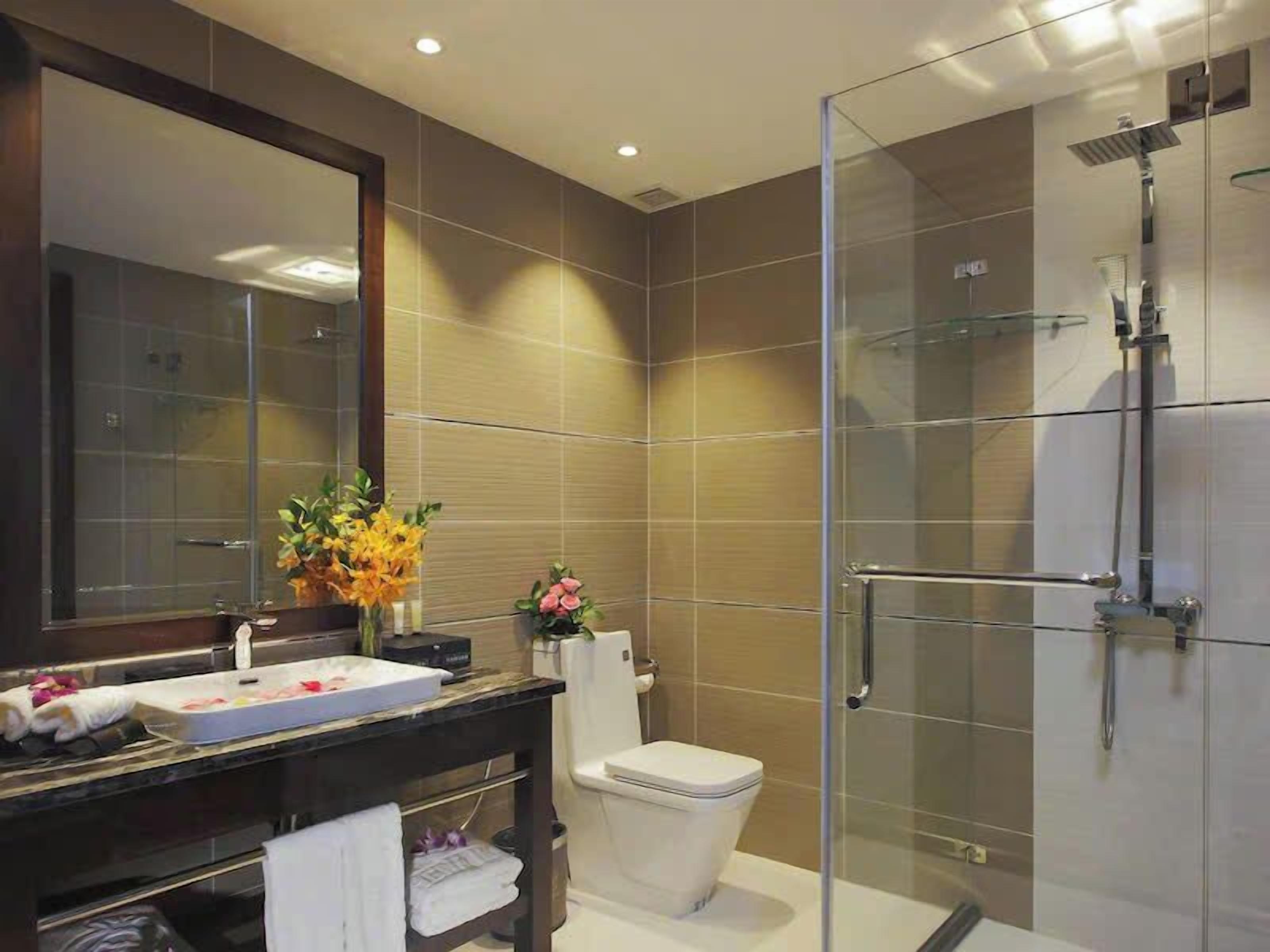 Une salle de bain moderne avec une douche à parois de verre, des toilettes blanches et un meuble-lavabo avec un miroir et un évier.