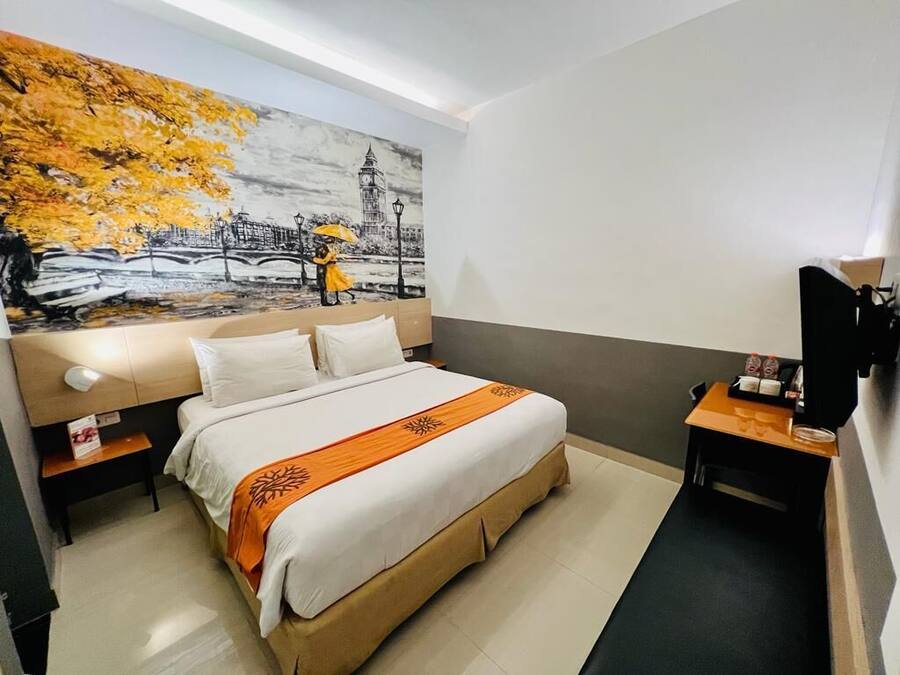 Une chambre d’hôtel équipée d’un lit, d’une table de chevet, d’un bureau et d’un téléviseur fixé au mur.
