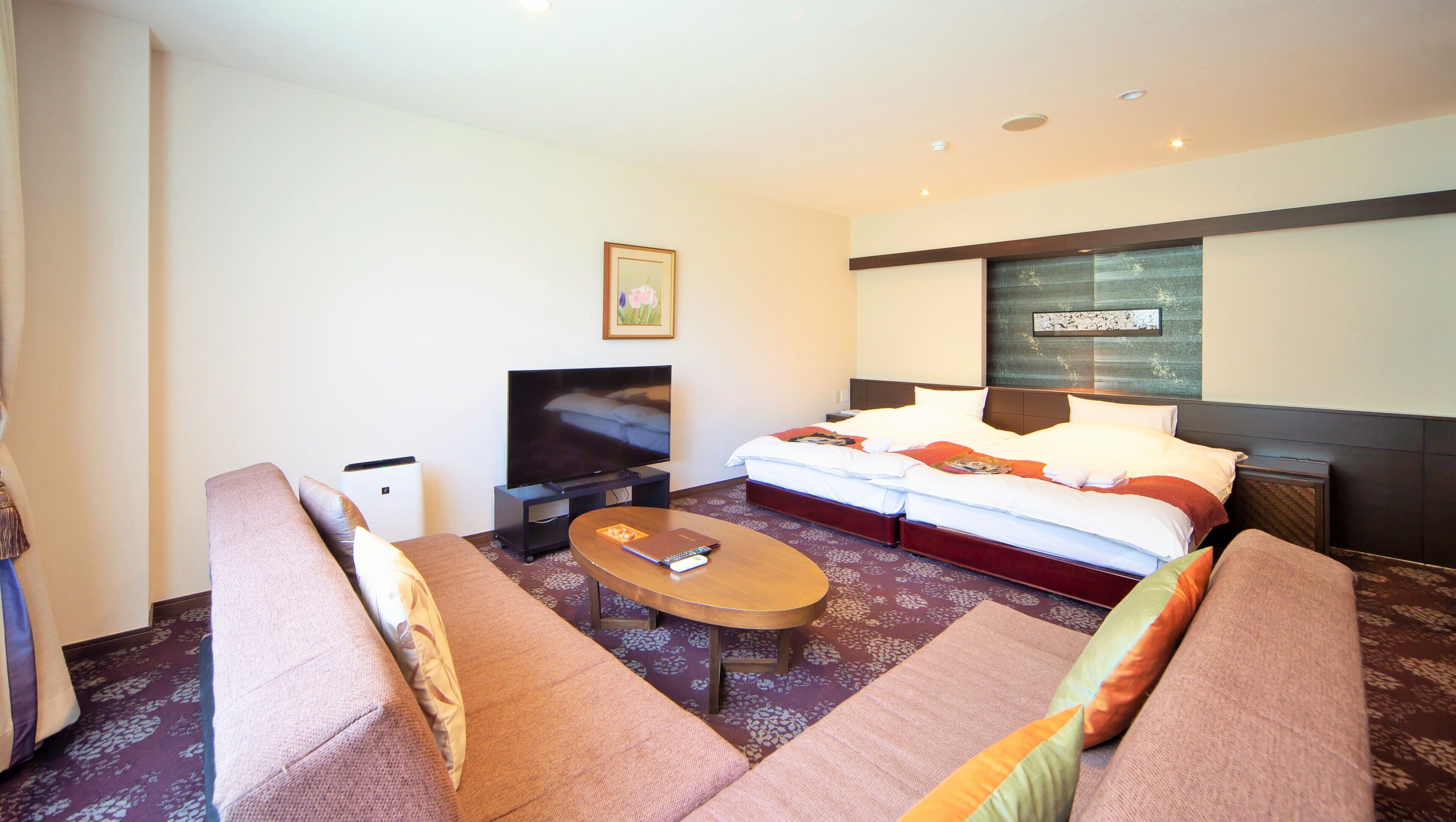 Een hotelkamer met een bed, een televisie, een bank en een salontafel.