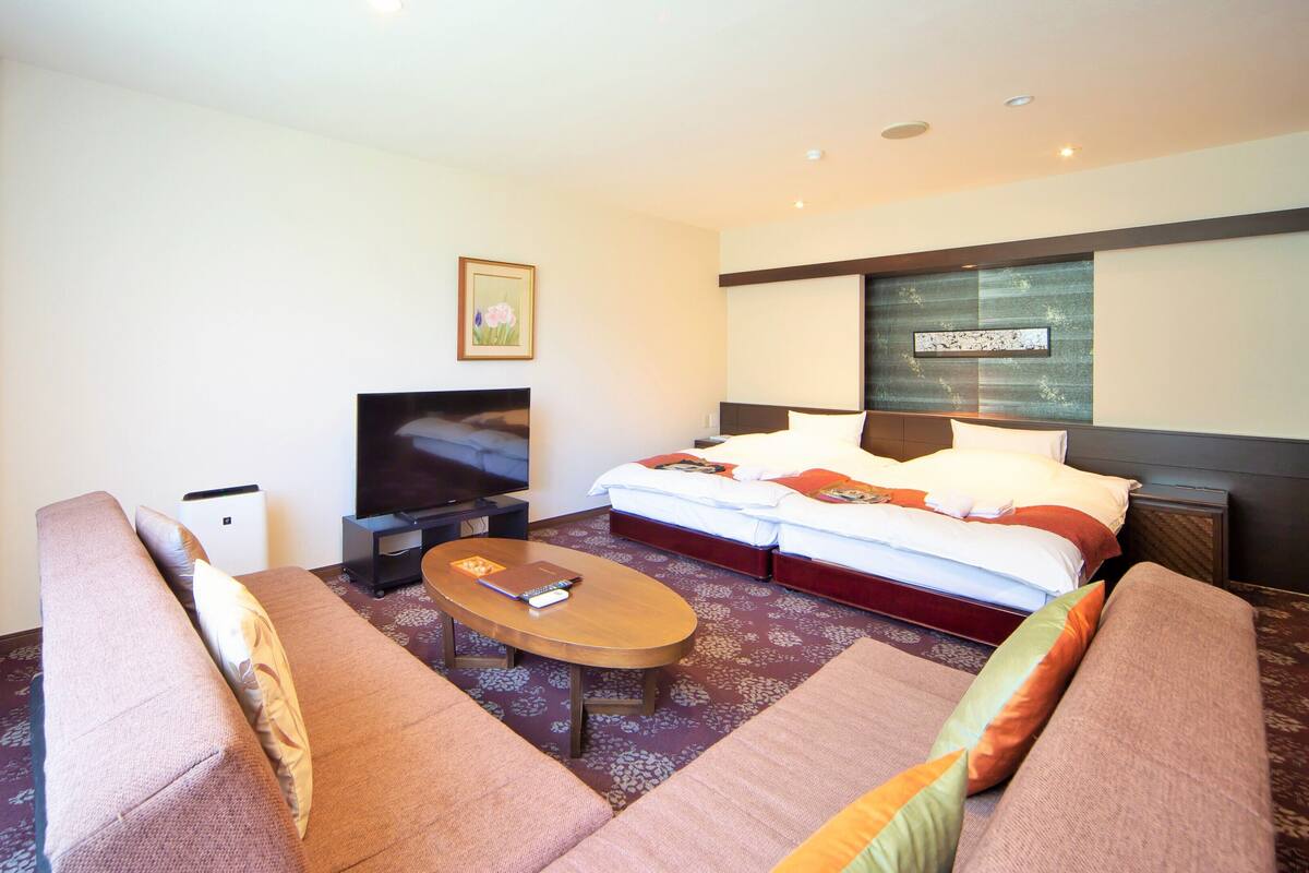 Une chambre d’hôtel avec un lit, une télévision, un canapé et une table basse.