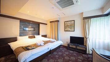 A hotel room with a large bed, a flat-screen TV, a desk, and a window with curtains.